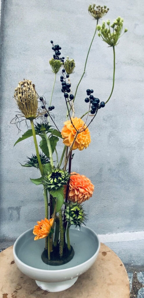 Floral-Design: hohes, puristisch gearbeitetes Gesteck mit Dahlie, wilder Möhre im Kenzan Steck-Igel